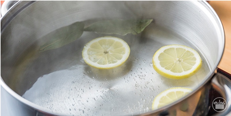Hervir agua en una olla con laurel y limón.