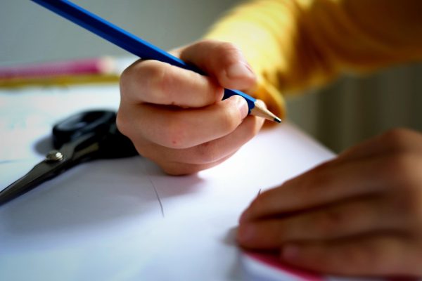 Niño escribiendo y haciendo los deberes para el colegio. La vuelta al cole